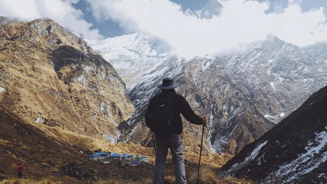 A trekker standing on a mountain trail with a daypack