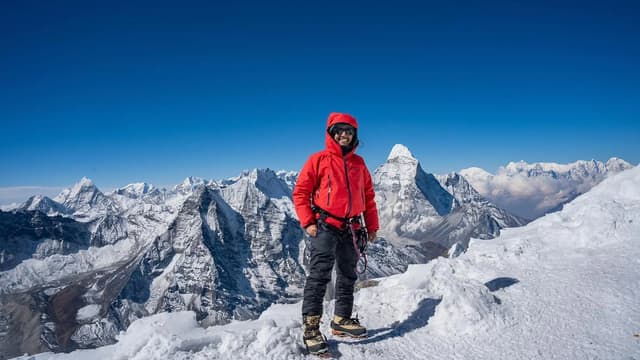 Trekker on the summit ridge of Island Peak in Nepal with Himalayan giants behind