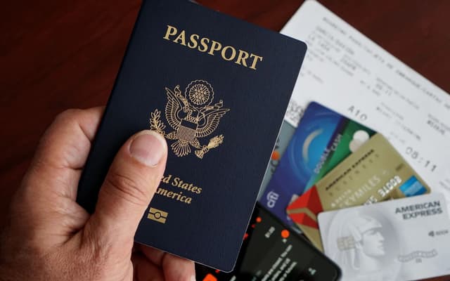 A passport, credit cards, tickets and a phone laid out on a table