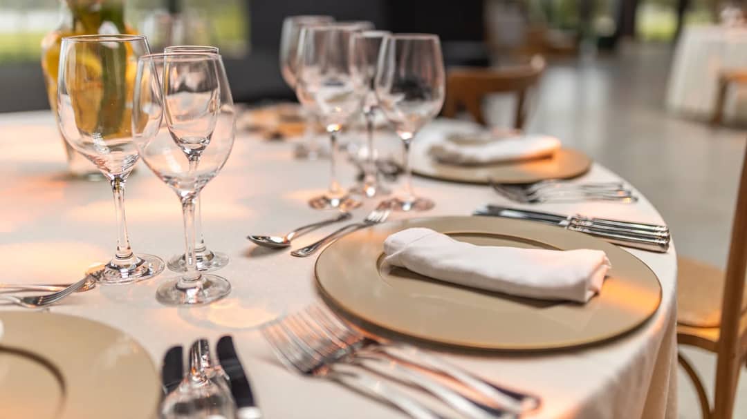 A restaurant table set for fine dining with glassware and napkins