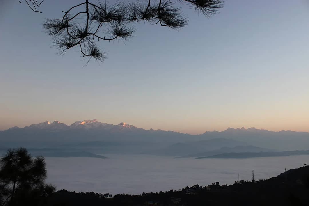 Snow peaks catching the first light above a sea of cloud, seen from Bandipur at dawn