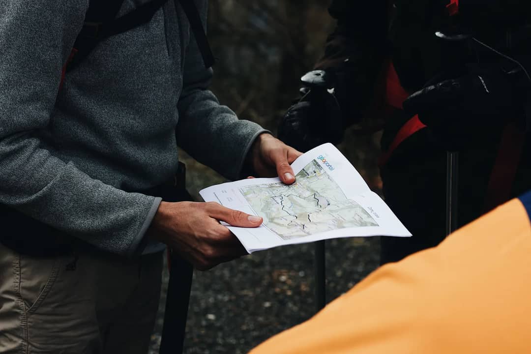 A group of hikers planning their route with a paper map outdoors