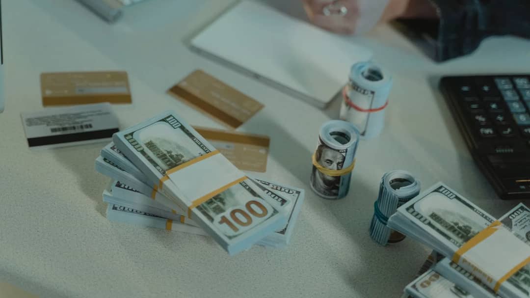 Credit cards, rolled banknotes and a calculator on a desk