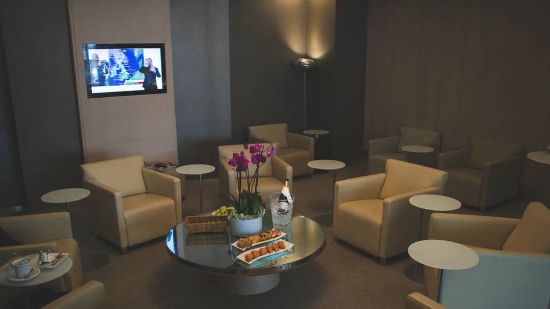 A quiet airport lounge with beige leather armchairs, small tables and a bowl of orchids