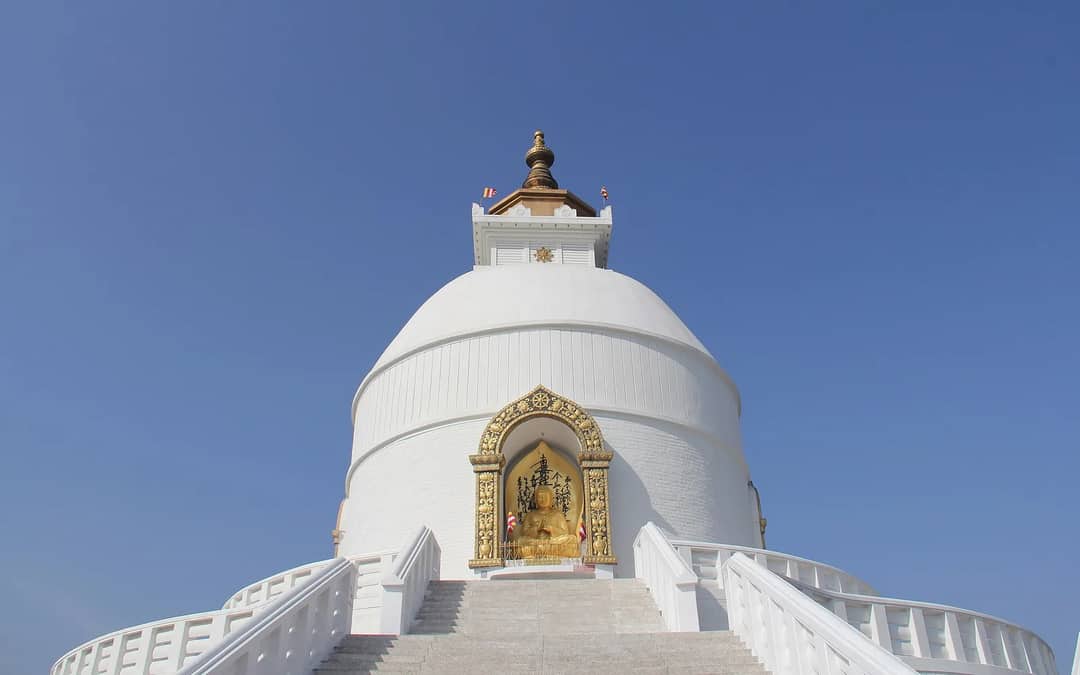 The white dome of the World Peace Pagoda above Pokhara, with a golden Buddha in its niche