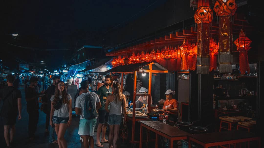 Tourists walking through a lantern-lit night market in Pai, Thailand