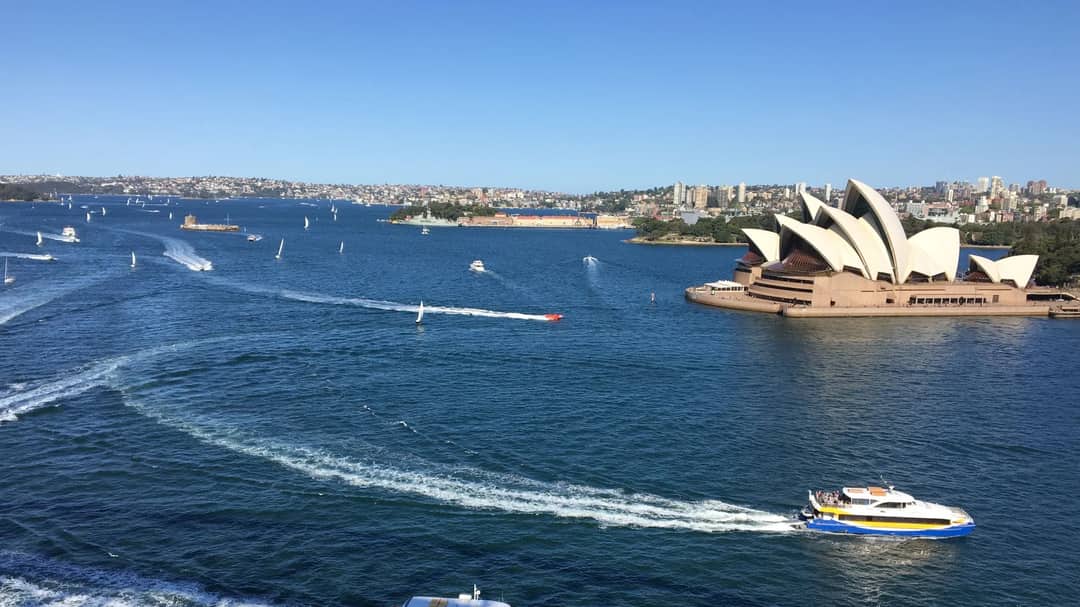Aerial view of Sydney Harbour with the Opera House and ferries under a clear sky
