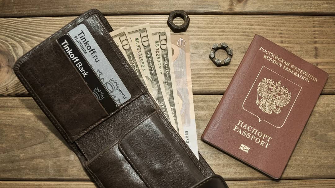 A leather wallet with bank cards, foreign banknotes and a passport on a wooden table