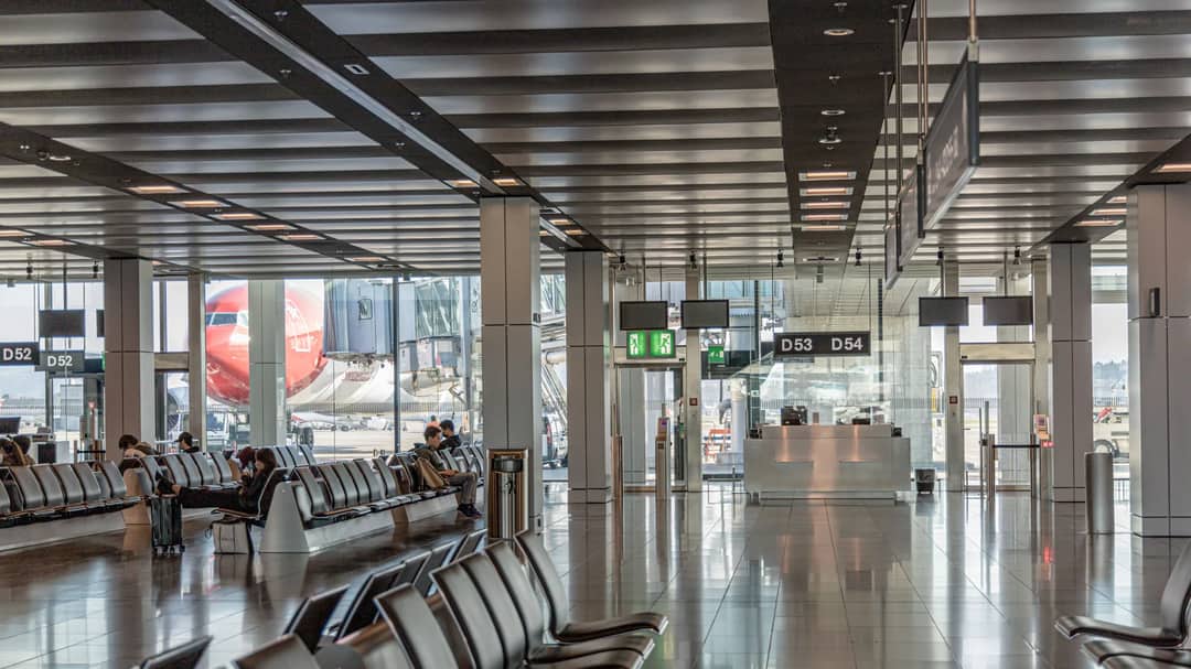 An empty airport terminal with rows of seats and a plane visible through the glass