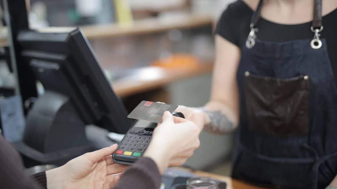 A customer paying by credit card at a shop counter