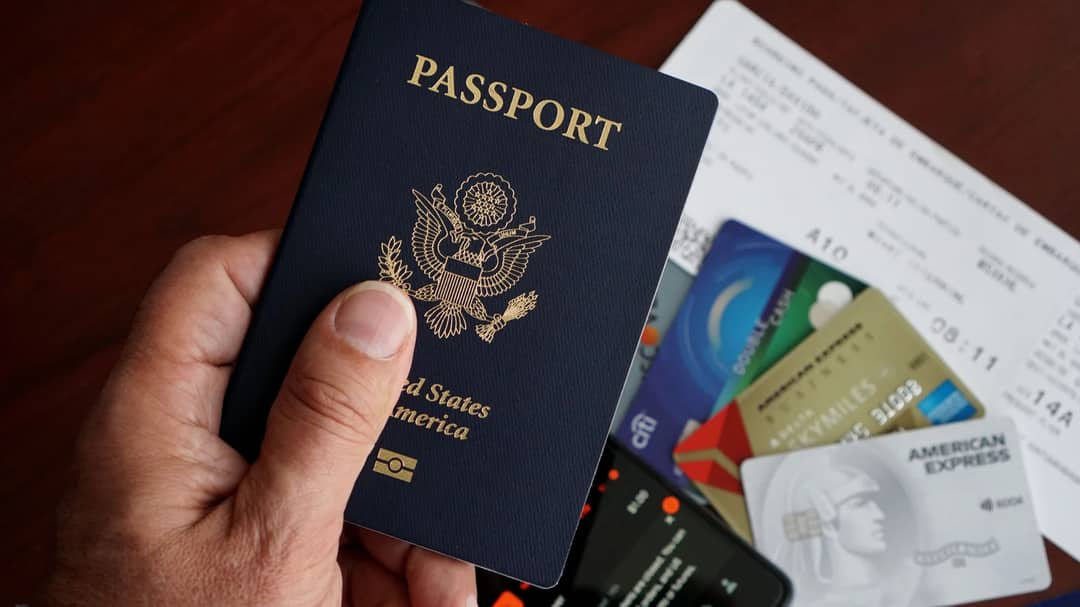 A passport, credit cards, tickets and a phone laid out on a table