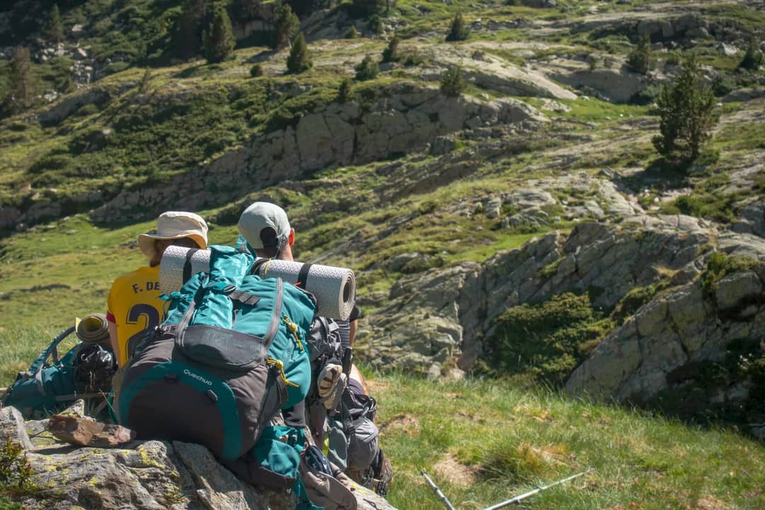 Two backpackers taking a break on a mountain hike and looking at the view