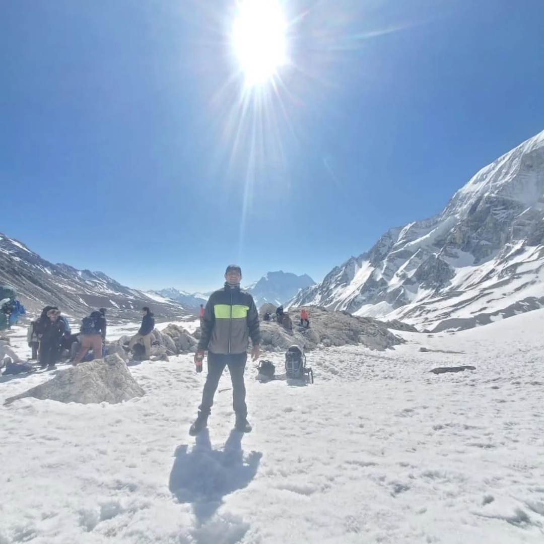 First light and sunburst over trekkers on the snowy Larkya La pass
