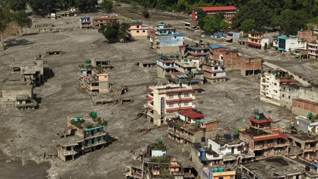 Aerial view of Devighat in Nuwakot after the flood, multi-storey buildings standing in a flat grey plain of silt
