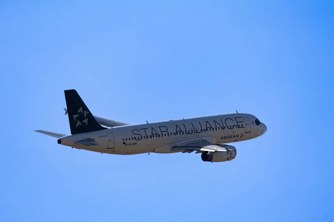 Aegean Airlines airplane soaring through a bright blue sky, showcasing air travel and aviation.