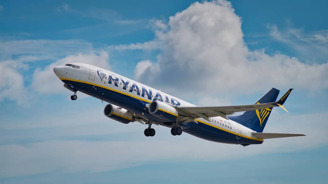 A Ryanair airplane ascends into the sky, showcasing its undercarriage and wing details.