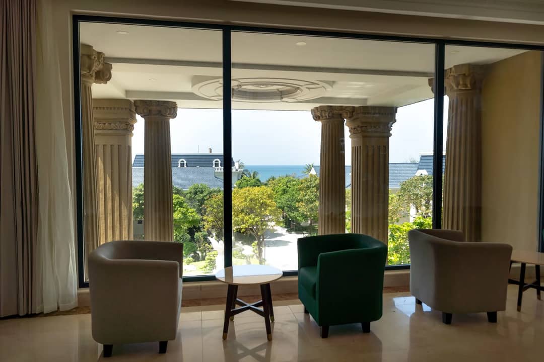 Chic interior with armchairs, facing picturesque ocean view through classic columns.