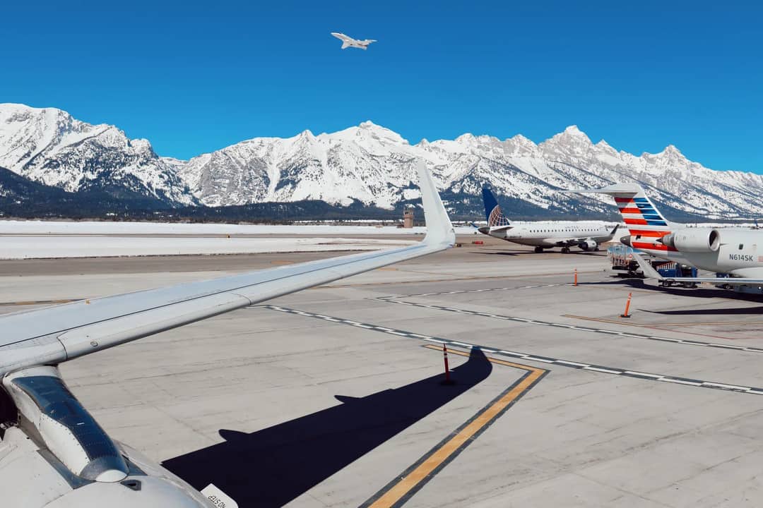 Airplanes at Jackson Airport with scenic snowy peaks in the background.