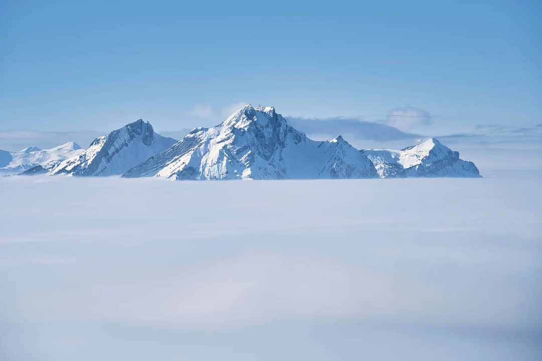 Serene view of snowy mountain peaks rising above a sea of clouds, showcasing natural beauty.