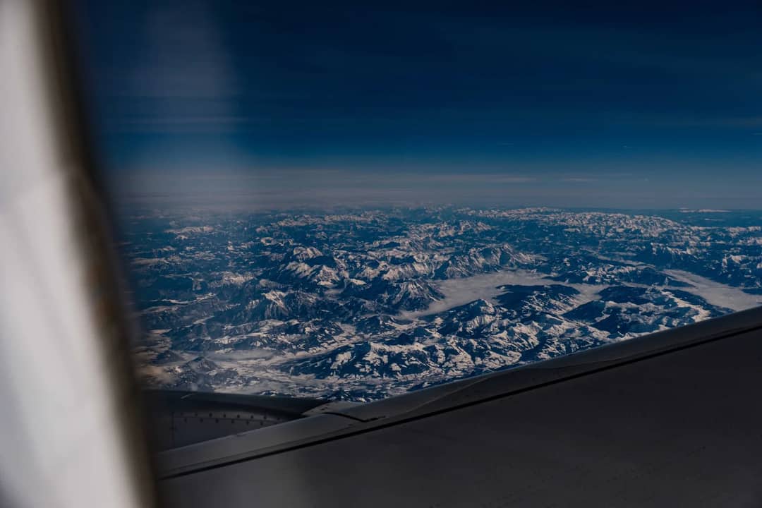 The view from an aircraft window over mountains — arriving by air is what compresses days of acclimatisation into a few hours
