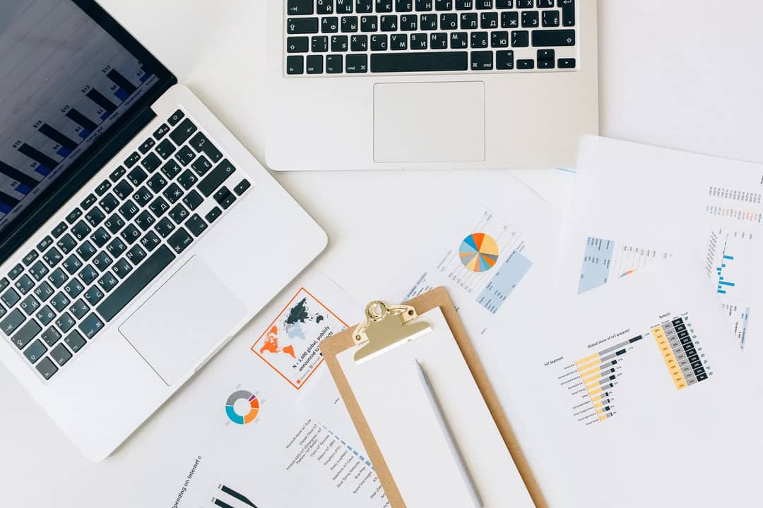 Laptops, printed charts and a clipboard on a desk