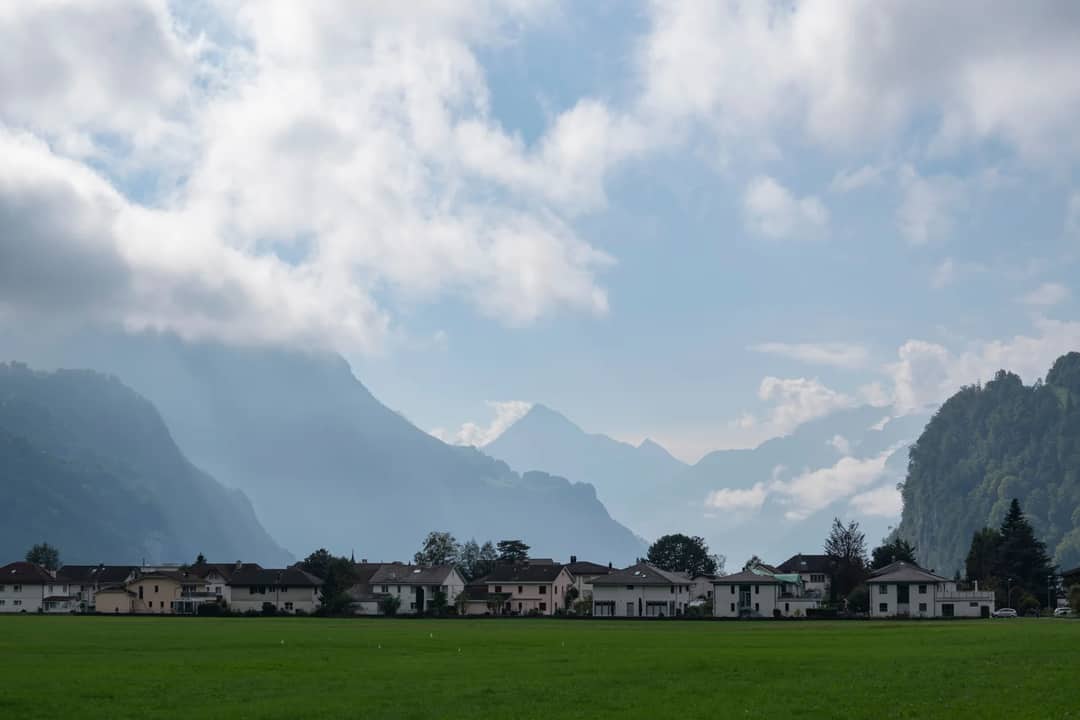 Picturesque alpine village with mountains in the background and a cloudy sky, capturing serene natural beauty.