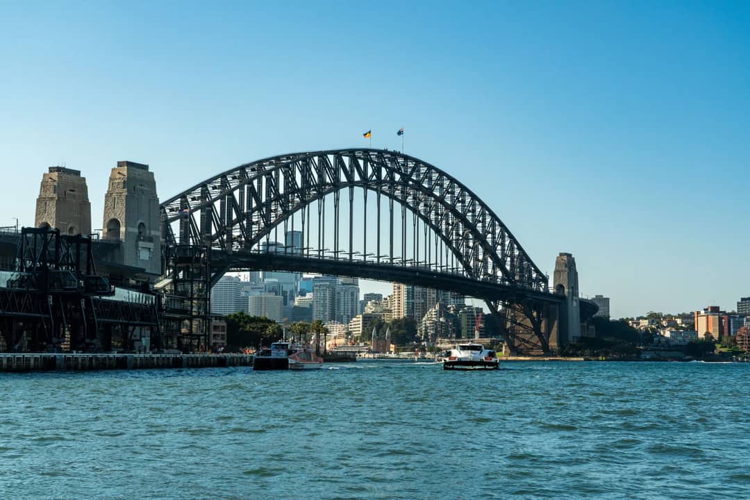 View of Sydney Harbour Bridge with city skyline and boats on a clear day.