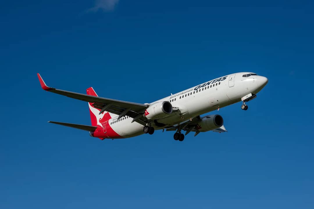 A commercial airplane flying against a clear blue sky, showcasing modern aviation.
