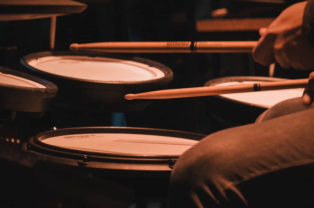Musician playing drums with drumsticks in a focused close-up shot, capturing the essence of rhythm and music.