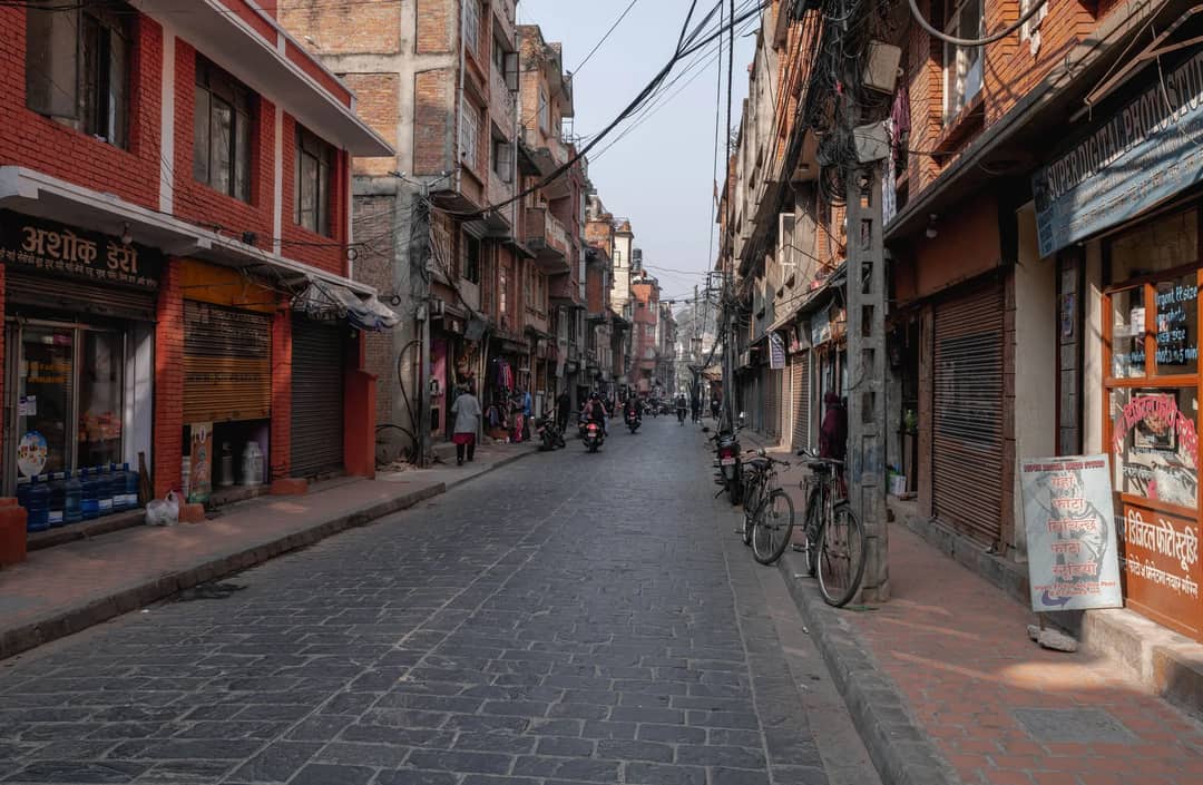 Bustling street with shops, bikes, and people in Kathmandu, Nepal.