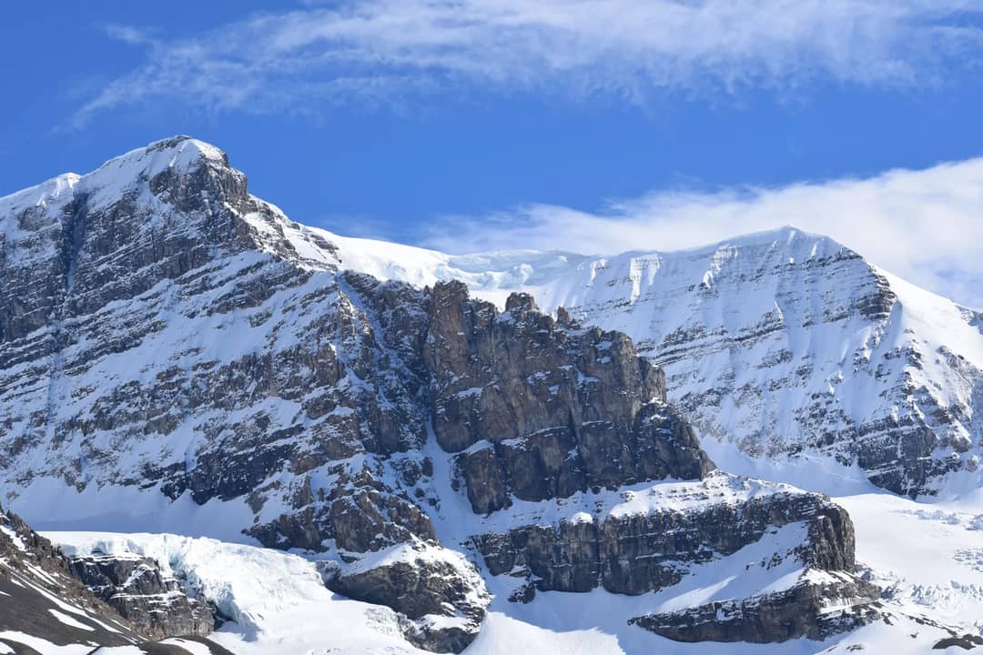 Breathtaking view of snow-covered Rocky Mountains under a vibrant blue sky in Alberta, Canada.