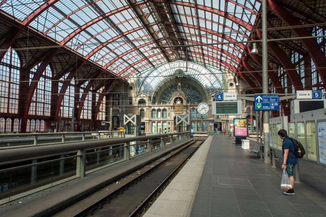 Wide view of Antwerpen Central Railway Station with a person waiting on the platform.