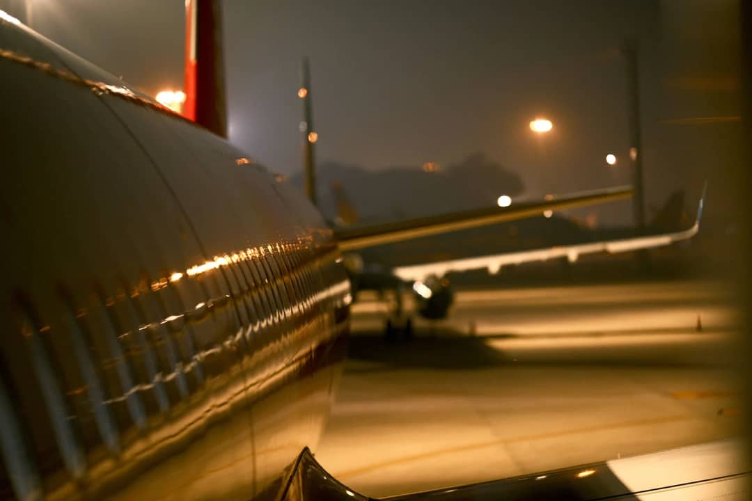 Aviation-themed night scene with airplane wings and runway lighting at Vietnam airport.