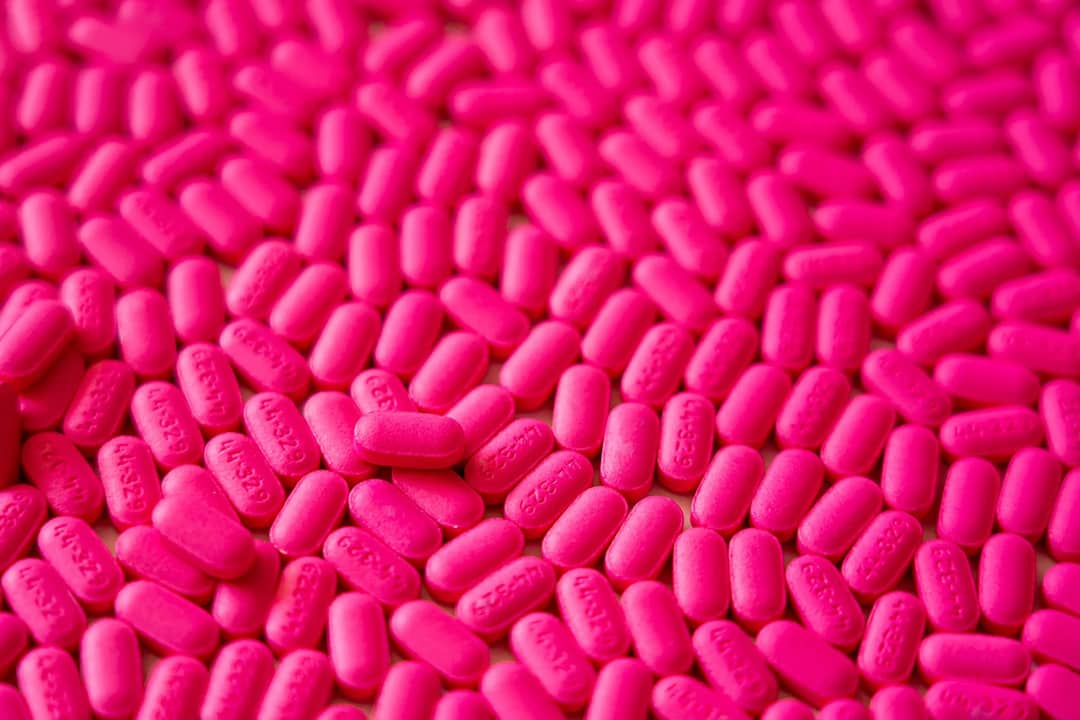 Close-up of vibrant pink pills, showcasing their texture and color.