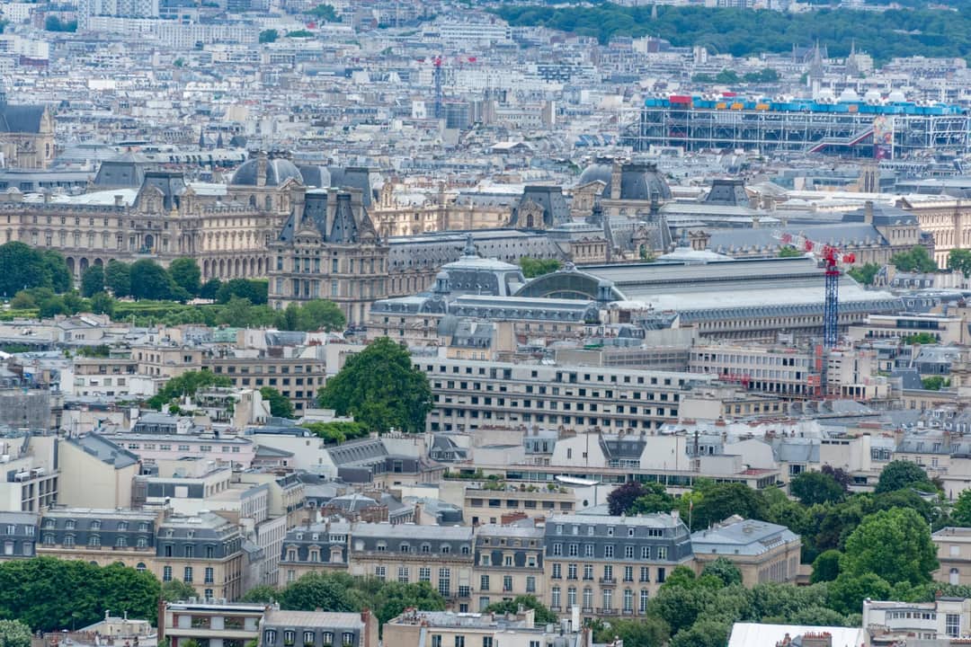 Aerial view of Paris showcasing the Louvre Museum and iconic cityscape in a summer setting.