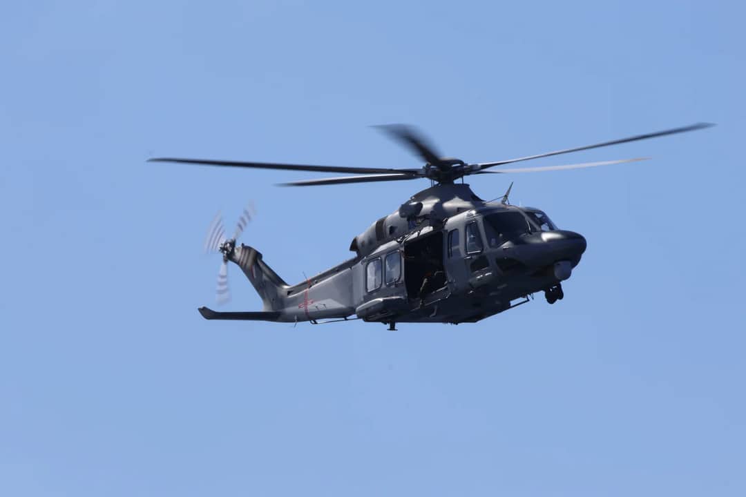 A sleek military helicopter soaring through a clear blue sky, displaying power and precision.