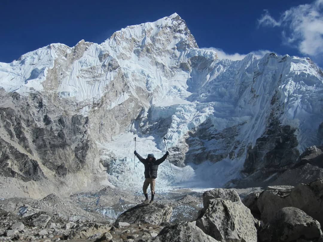 A man standing on top of a mountain with his arms in the air