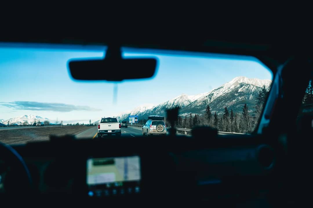 The view through a car windscreen on a highway towards snow-capped mountains