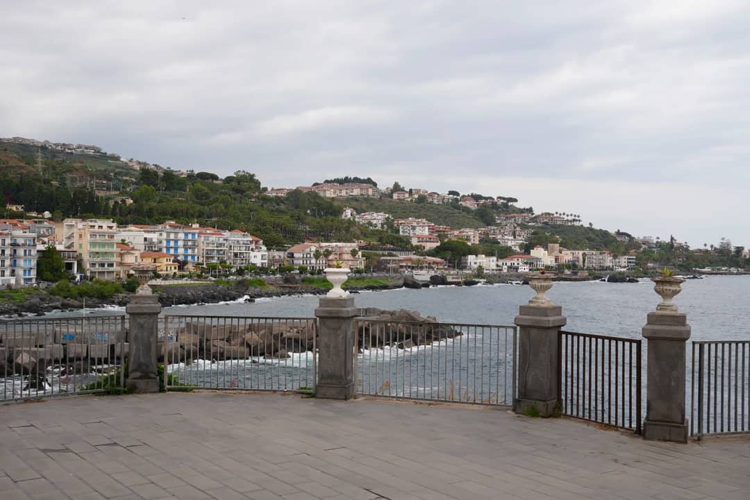 Beautiful coastal view of Acireale with sea and buildings on a cloudy day.