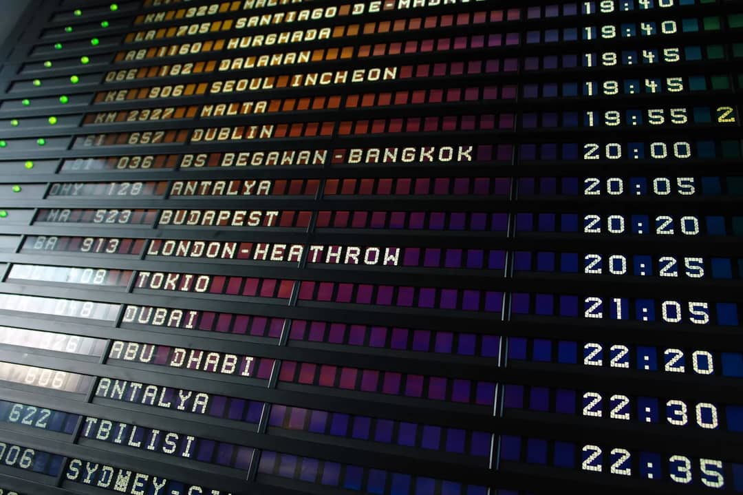 An airport departure board listing international flights