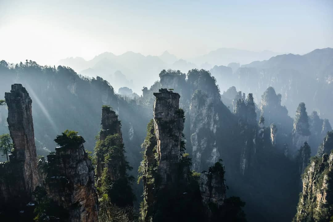Tall sandstone pillars rising above a misty valley in Zhangjiajie National Forest Park