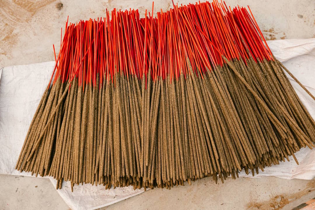 A collection of handcrafted incense sticks with vibrant red tips spread on white fabric, creating a striking visual.