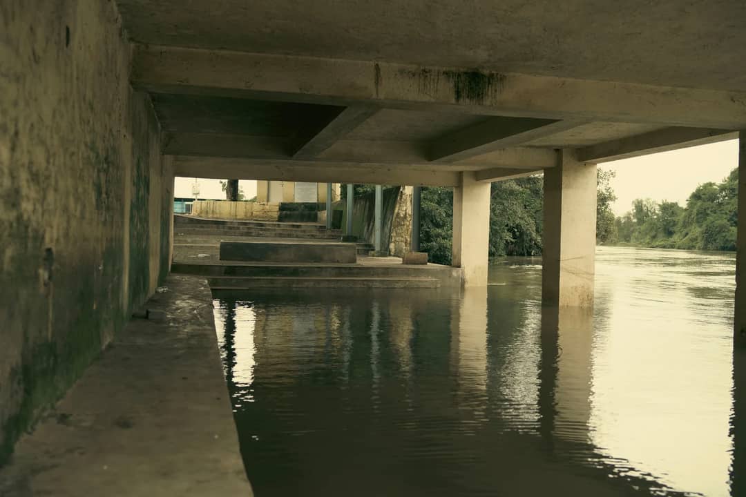 An artistic view of a concrete structure over a calm, flooded river.
