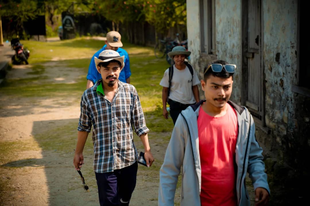 A group of diverse friends enjoying a sunny day walk outdoors in casual attire and hats.