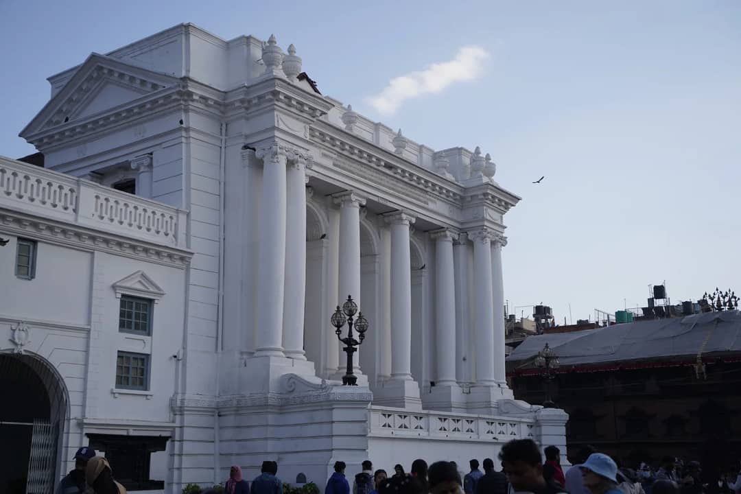 Capture of a classic historic building with white pillars under a blue sky.