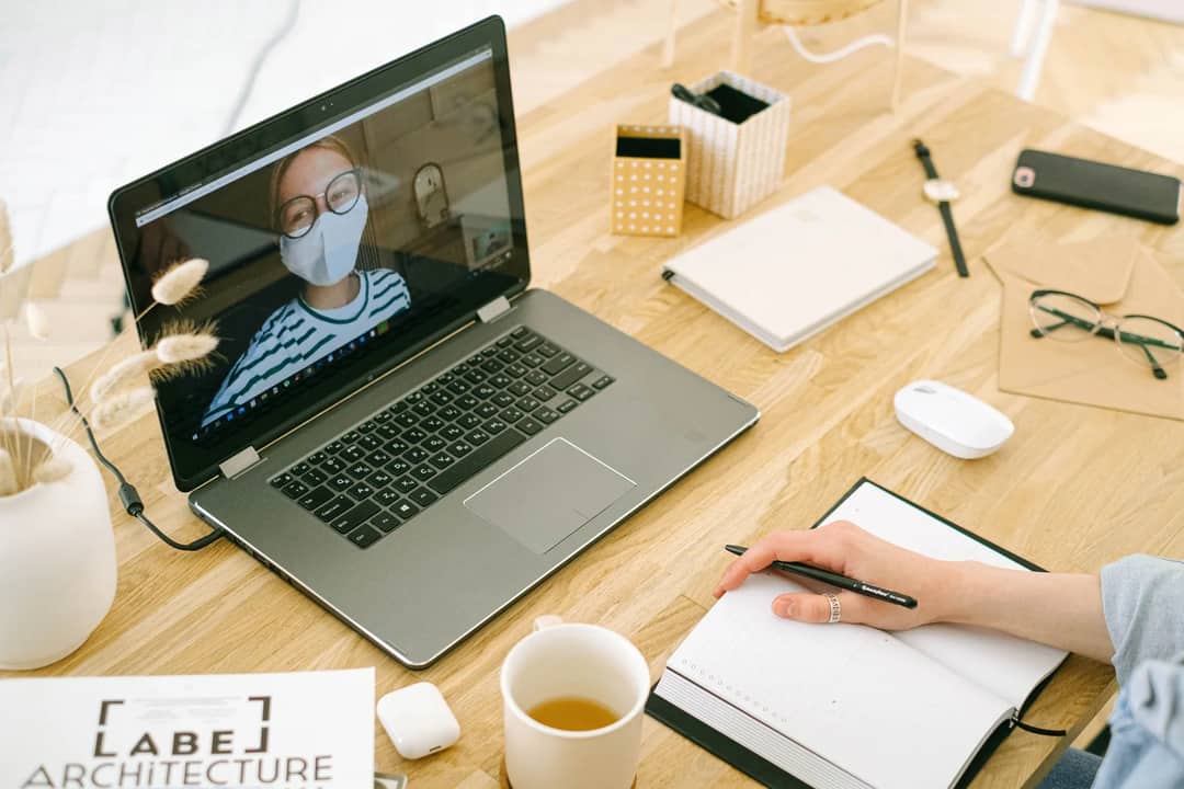 A laptop open on a video call on a desk