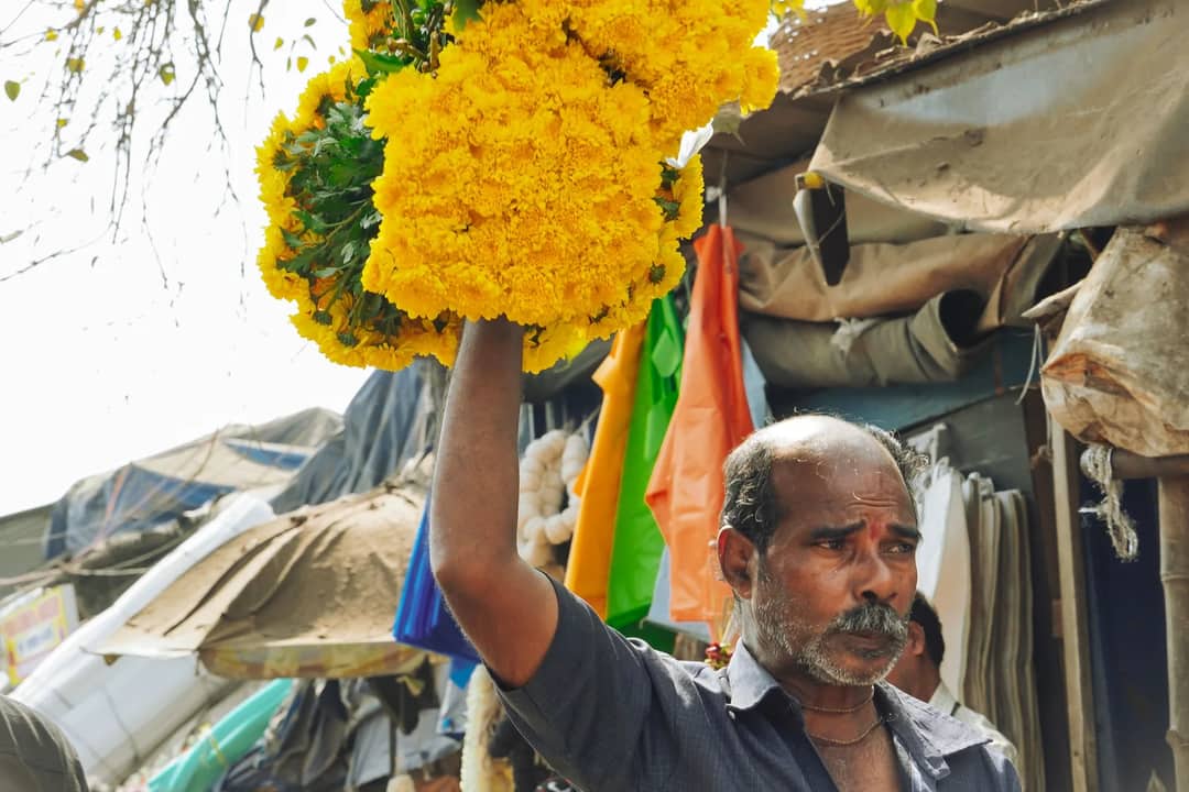 A vendor carrying bundles of marigold garlands