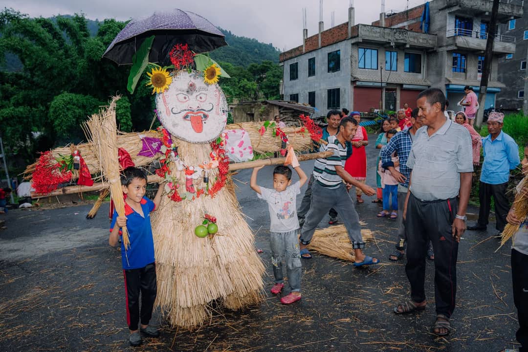 A festive gathering around a decorated straw figure in a village setting, showcasing cultural heritage.