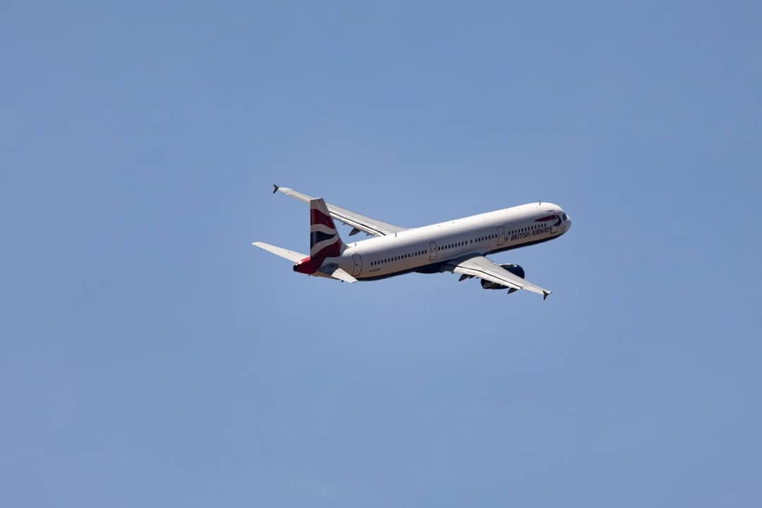 Wide shot of a commercial airplane flying high in a clear blue sky, showcasing modern aviation.