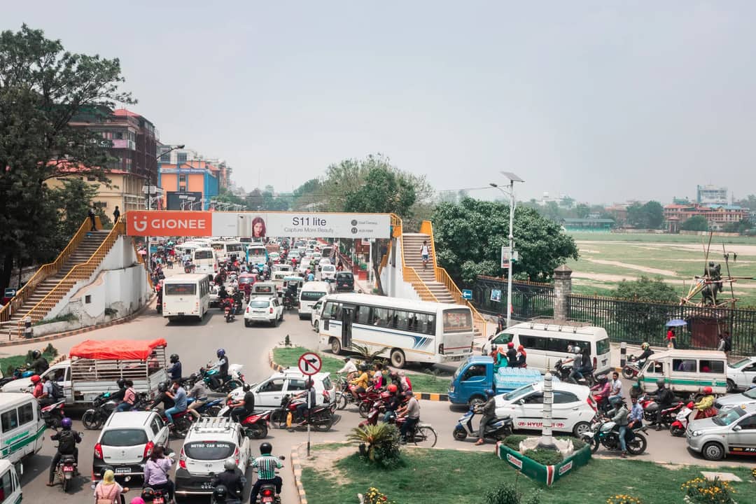 A busy urban street in Kathmandu full of cars and motorcycles, showcasing vibrant city life.